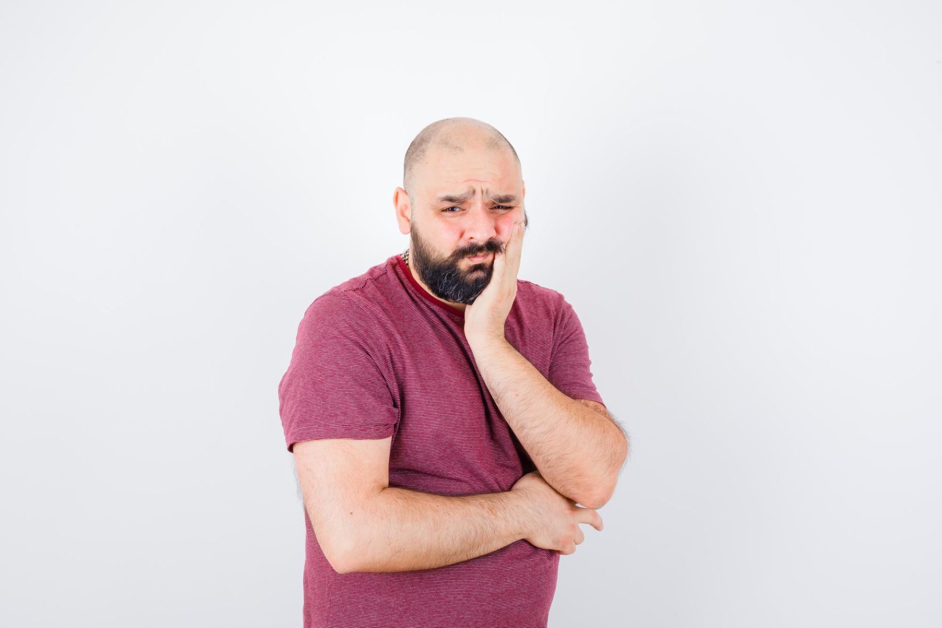 Man holding his cheek and wincing in pain from a cracked tooth
