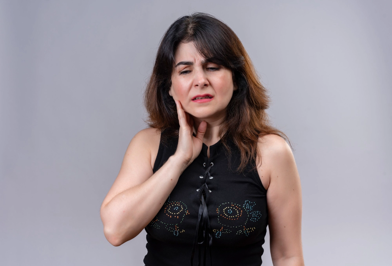 Woman pressing her jaw joint, illustrating TMJ pain