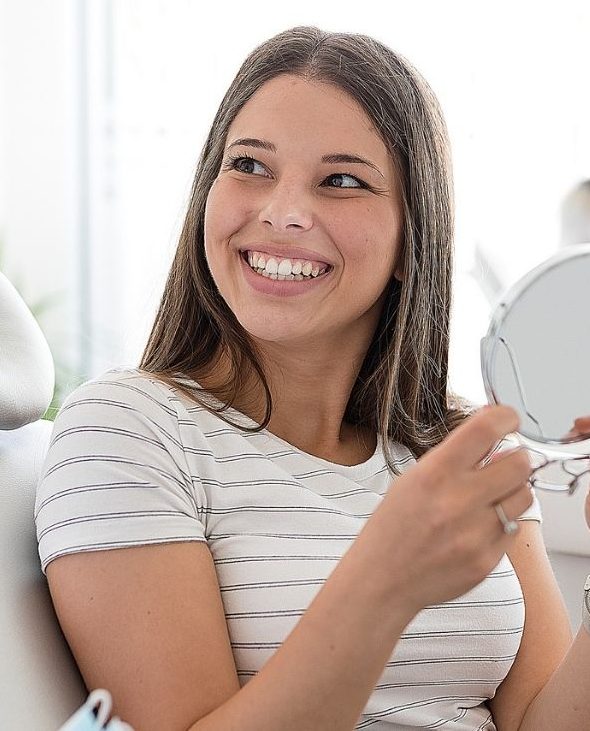 Patient reviewing her smile in a mirror during a visit to South Florida Smile Spa