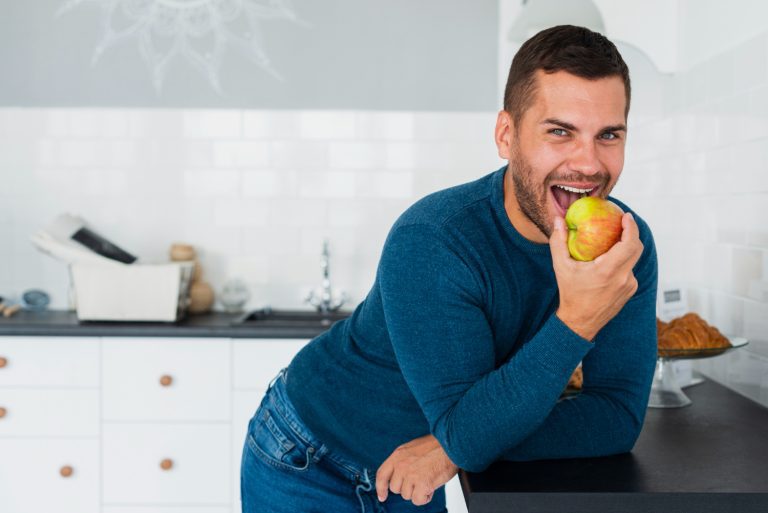 Man with dental implants eating an apple