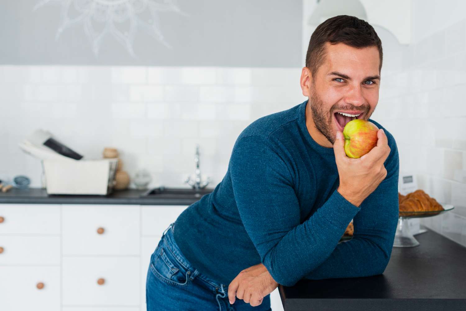 Man with dental implants eating an apple