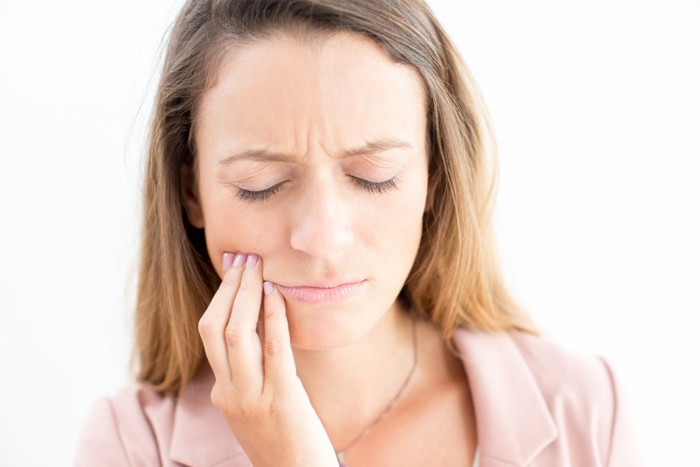 adult woman holding her cheek due to dental abscess