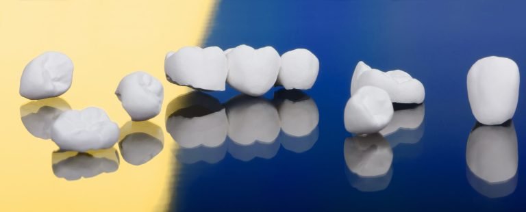 Zirconia dental crowns and a three-unit bridge arranged on a gold and navy background, illustrating dental crown materials.